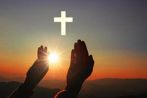 silhuett av mänskliga händer handflatan upp be och dyrkan av korset, nattvardsterapi välsigne gud att hjälpa, tro, förlåtelse, frihet, hopp och tro, kristen religion koncept på solnedgång bakgrund. foto