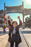 porträtt Foto av senior asiatisk kvinnor med beijing zhengyang Port jianlou i qianmen street.qianmen gata är känd gata i beijing huvudstad stad av Kina