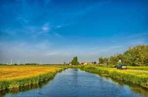 holländskt landskap med en kanal och gräsfält med spegelreflekt foto