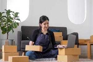 porträtt av asiatisk ung kvinna sm som arbetar med en låda hemma workplace.start-up småföretagare, småföretagare SM eller frilansande företag online och leverans koncept. foto