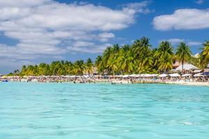 människor som simmar nära den vita sandstranden med parasoller, bungalowbar och kokospalmer, turkosa karibiska havet, isla mujeres ö, karibiska havet, cancun, yucatan, mexico foto