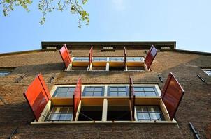 skön byggnad med öppen Sol persienner och fönster i amsterdam, holland nederländerna foto