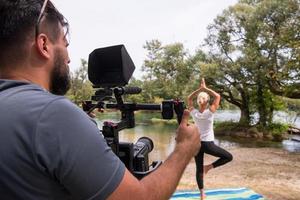 ung videographer inspelning medan kvinna håller på med yoga övning foto