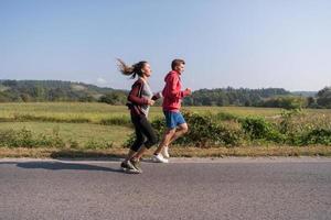 ungt par joggar längs en landsväg foto