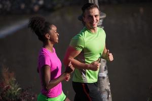 ung leende multietnisk par joggning i de stad foto
