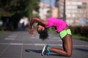 sportig ung afrikansk amerikan kvinna stretching utomhus foto
