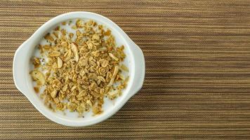 morgonmat mandelflingor och mjölk i vit skål på träbord. foto
