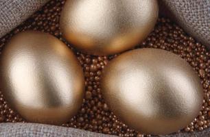 tre gyllene ägg på guld sand. foto