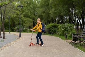 pojke i en gul tröja med en ryggsäck på ryggen går till skolan. tillbaka till skolan koncept foto