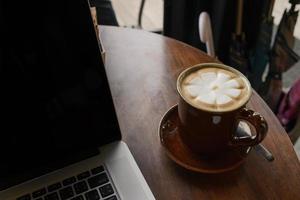 kaffekopp och laptop på träbord i kafé. affärsidé foto