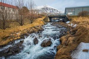 de flod strömmande från de bergen i stodvarfjordur stad av öst island. foto