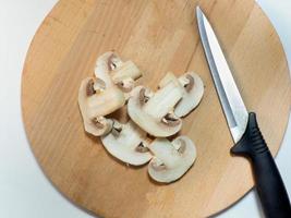 champignons och kniv på en skärande styrelse. kök redskap foto