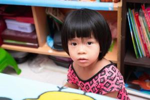asiatisk unge flicka är Sammanträde i en rörig rum. begrepp av kvalitet av liv och höjning ung barn. de kort håriga barn är 4 år gammal. foto