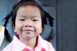 asiatisk flicka log ljuv. barn har gummi i de huvud av de öga efter vakna upp. barn 3 år gammal ha på sig rosa skjortor. foto