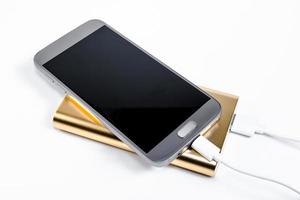 gyllene powerbank med smart telefon på bakgrund foto