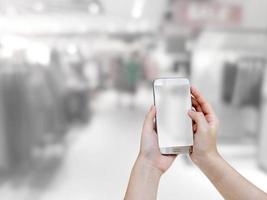 hand som håller mobil smart telefon med köpcentrum suddig bakgrund foto