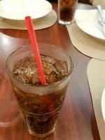 närbild glas av cola med is kuber och sugrör foto