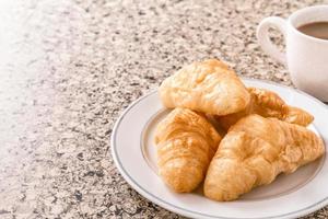 frukost med kopp av kaffe, croissant på de tabell. foto