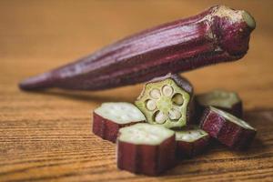 färsk röd okra på trä- bakgrund. foto