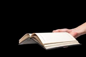 manlig hand innehav en tom anteckningsbok på en svart bakgrund. foto