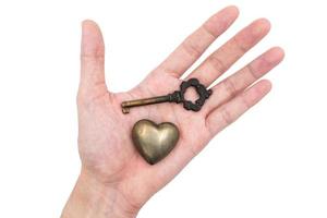 manlig hand innehav metall hjärta med nyckel på vit bakgrund, liknelse kärlek begrepp. foto