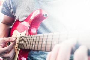 stänga upp av manlig händer spelar elektrisk gitarr, blossa från de solljus, selektiv fokus foto