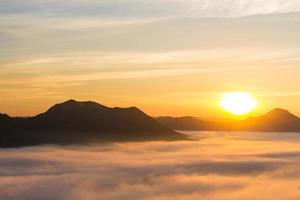 skön landskap med berg, dimma och Sol i de morgon. resa bakgrund. foto