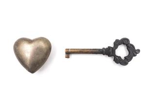 metall hjärta med nyckel på vit bakgrund, liknelse kärlek begrepp. foto
