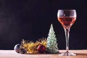 glas av vin med jul dekorationer på de trä- tabell, svart bakgrund, fri Plats för text foto