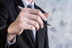 stänga upp av affärsman hand innehav penna på grunge bakgrund. foto