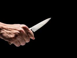 manlig hand innehav kniv på svart bakgrund. foto