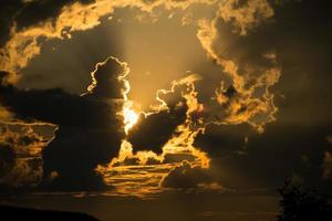 skön solnedgång - de orange ljus av de Sol genom de moln foto