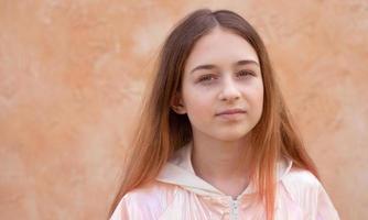 en Tonårs flicka i en rosa jacka på en beige bakgrund. porträtt av en skön flicka. foto