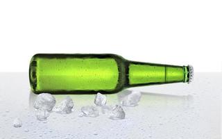 öl flaska med vatten droppar och is kuber på vit bakgrund foto