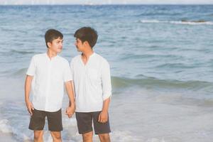 homosexuella porträtt ungt asiatiskt par står tillsammans på stranden på sommaren, asien gay håller händerna går havet på fritiden och koppla av med romantiska och glada i semester till sjöss, hbt med juridiska koncept. foto