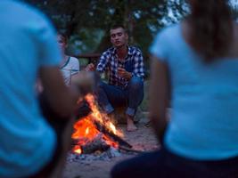 ung vänner avkopplande runt om lägereld foto