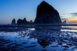 en blå kväll solnedgång scen på höstack sten i kanon strand, Oregon. foto