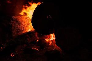 bål med en gnistor på natt. värme från brinnande loggar och kol i de mörk foto