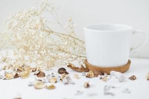 mysigt Hem med en kopp av kaffe och blomma gren. hygge vinter- eller höst stil foto