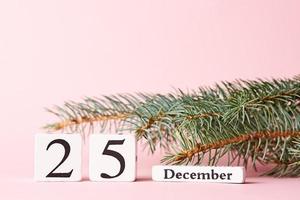 jul bakgrund. jul träd gren och kalender med datum 25 december på en rosa bakgrund foto
