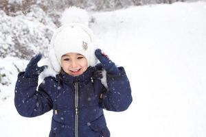 liten flicka i de kall vinter- i värma kläder, med pälsfodrad öra dynor. glädje, skratt, barns känslor, vinter- spel i de snö. frostbeständig vattentät membran Kläder. kopia Plats foto