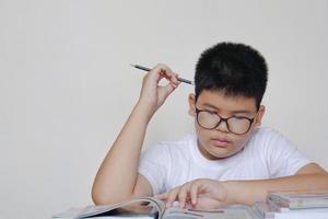 asiatisk pojke läsa en böcker och tänka. kreativa, utbildning, lärande koncept. foto