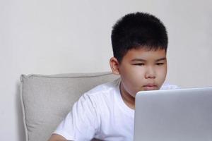 närbild ansikte söt pojke ha kul tittar på laptop. utbildning, lärande och teknik koncept. foto