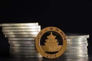 kinesiska guldpandamynt framför silvermynt foto