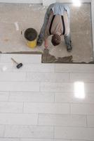arbetare som installerar de keramiska träeffektplattorna på golvet foto
