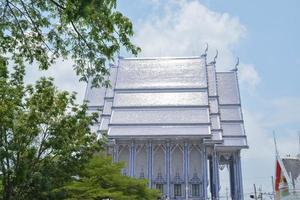 se av blå keramisk kyrka med stor träd på bredvid, wat pak nam khaem nu tempel, Chanthaburi, thailand. foto