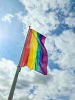 regnbåge stolthet flagga illustration. HBTQ gemenskap symbol i regnbåge färger mot de blå himmel . foto