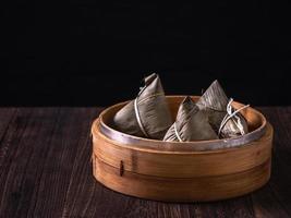 zongzi - kinesisk ris klimp zongzi i en ångkokare på trä- tabell svart retro bakgrund för drake båt festival firande, stänga upp, kopia Plats. foto