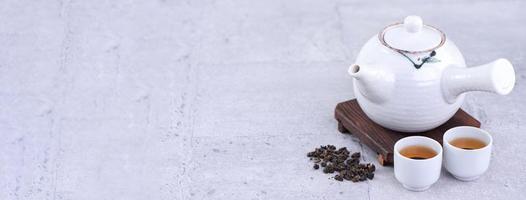 varm te i vit tekanna och koppar på en sikt över ljus grå cement bakgrund, närbild, kopia Plats design begrepp. foto