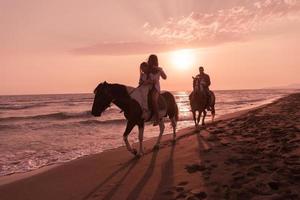 de familj spenderar tid med deras barn medan ridning hästar tillsammans på en sandig strand. selektiv fokus foto